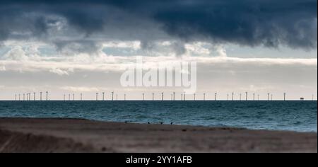 turbine eoliche offshore che generano energia elettrica in mare cielo scuro sopra il molo panoramico in cemento coltivato in primo piano in condizioni di illuminazione contrastanti Foto Stock
