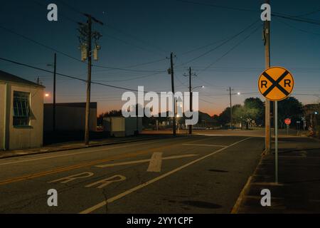 Un tranquillo attraversamento ferroviario e incrocio al crepuscolo, catturato a Brunswick, Georgia Foto Stock