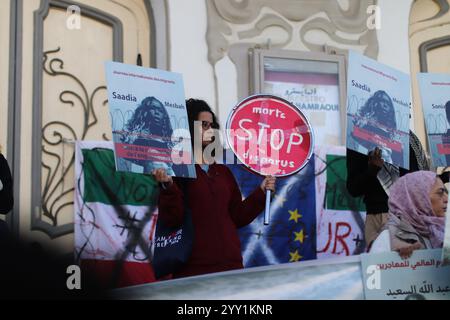 Tunisi, Tunisia, 18 dicembre 2024. Attivisti e manifestanti si riuniscono fuori dal teatro in viale Habib Bourguiba chiedendo diritti per i migranti che intraprendono il pericoloso attraversamento del Mediterraneo per raggiungere l'Italia e l'Europa. I partecipanti hanno denunciato il trattamento dell'Italia nei confronti dei migranti irregolari che raggiungono le sue coste, gli accordi della Tunisia con l'Italia e l'UE per arginare il flusso di arrivi irregolari in Europa e il "nuovo Patto sull'immigrazione e l'asilo” dell'UE. La manifestazione ha coinciso con la giornata internazionale dei migranti Foto Stock