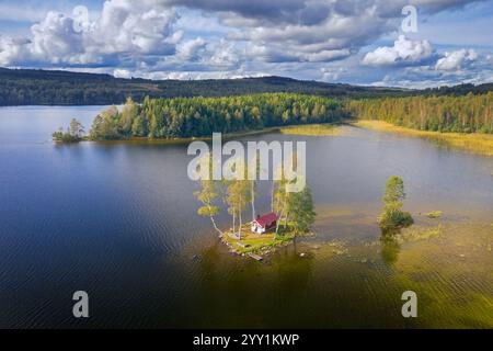 Vista aerea su una piccola cabina tradizionale in legno rosso su una piccola isola nel lago in autunno/autunno, Värmland, Svezia centro-occidentale, Scandinavia Foto Stock