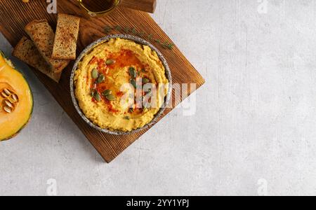 Hummus di ceci di zucca fatto in casa in una ciotola su tavola di legno su sfondo chiaro. Vista dall'alto, copia spazio. Foto Stock