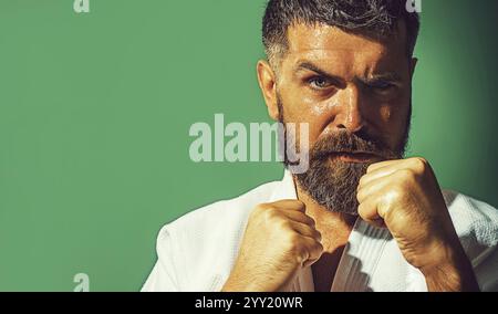 Primo piano ritratto di un serio uomo di karate in posizione di combattimento. Istruttore di karate maschile con pugni clenati pronti per l'allenamento di karate. Combattente di karate Foto Stock