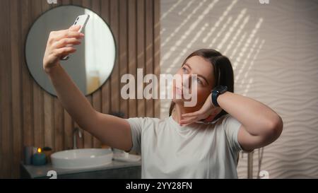 Donna caucasica beauty blogger vlogger modello influencer selfie foto cellulare social media SkinCare blog vlog in casa bagno spensierato felice Foto Stock