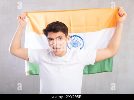 Lo spettatore maschio attivo e pieno di energia tiene in mano la bandiera nazionale dell'India e canta slogan popolare. Foto Stock