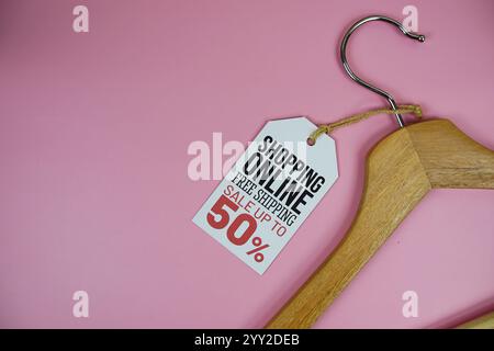 Vendita online fino al 50% sul prezzo con appendiabiti in legno vista dall'alto su sfondo rosa Foto Stock