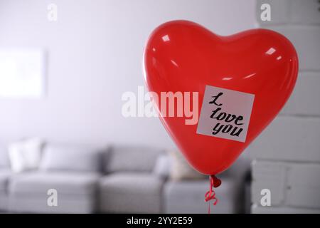 Palloncino ad aria a forma di cuore rosso con nota appiccicosa che dice che ti amo in camera. Spazio per il testo Foto Stock