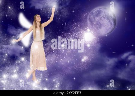 Incantevoli fate che proiettano le luci nel cielo buio con la luna piena. Bella ragazza con le ali Foto Stock