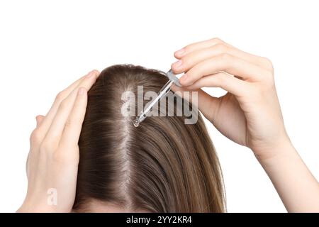 Problema di perdita dei capelli. Ragazza che applica il siero sulla linea di capelli su sfondo bianco, primo piano Foto Stock