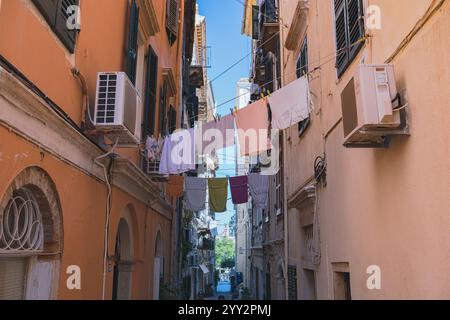 Via della città di Corfù in Grecia. Città vecchia, strada stretta, lavanderia colorata che si asciuga sulle linee che si estendono tra le case. Foto Stock