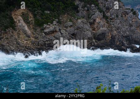 Una piccola isola rocciosa solitaria in mare aperto. Tempesta in mare, onde infurianti che si infrangono contro la piccola isola ed esplodono con spruzzi bianchi. Rock in A. Foto Stock