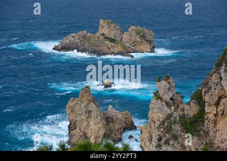 Una piccola isola rocciosa solitaria in mare aperto. Tempesta in mare, onde infurianti che si infrangono contro la piccola isola ed esplodono con spruzzi bianchi. Rock in A. Foto Stock