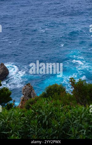 Una piccola isola rocciosa solitaria in mare aperto. Tempesta in mare, onde infurianti che si infrangono contro la piccola isola ed esplodono con spruzzi bianchi. Rock in A. Foto Stock