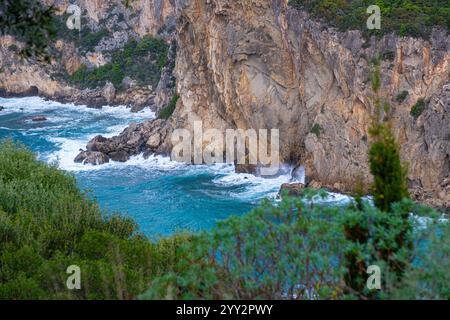 Una piccola isola rocciosa solitaria in mare aperto. Tempesta in mare, onde infurianti che si infrangono contro la piccola isola ed esplodono con spruzzi bianchi. Rock in A. Foto Stock