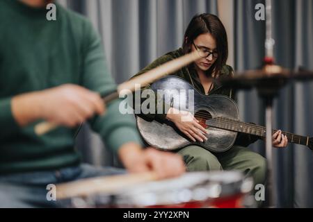 Musicisti che praticano insieme alla chitarra e alla batteria in studio di prova Foto Stock