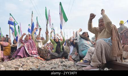 AMRITSAR, INDIA - 18 DICEMBRE: Gli agricoltori bloccano i binari ferroviari come parte della loro protesta "Rail Roko" a livello statale per spingere il Centro ad accettare le loro varie richieste, tra cui un prezzo minimo di sostegno legalmente vincolante (MSP) per le colture a devi Dasspura il 18 dicembre 2024 ad Amritsar, India. Ben 21 treni sono stati cancellati e molti sono stati a breve termine o di breve origine nelle divisioni ferroviarie di Ambala e Ferozepur, poiché gli agricoltori sono accovacciati su binari ferroviari in più di 50 posti in tutto il Punjab. La richiesta per la rotaia roko fu data dal Samyukta Kisan Morcha (non politico) e Kisan Mazdoor M. Foto Stock