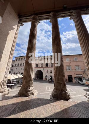 Vista delle antiche colonne romane con una vivace piazza cittadina e un cielo azzurro. Rappresenta la storia, l'architettura e la vita di tutti i giorni in un bellissimo set Foto Stock