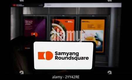 In questa immagine, una persona ha in mano un cellulare con il logo dell'azienda alimentare sudcoreana Samyang Roundsquare Co. Ltd. Davanti alla pagina Web. Foto Stock