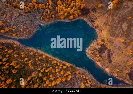 Prospettiva aerea di un lago turchese a forma di cuore, circondato da colorati alberi autunnali e sentieri, catturando la bellezza della natura. Foto Stock