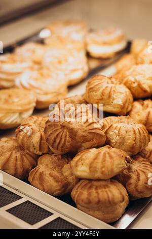 Un'allettante gamma di dolci presentati in una vetrina di una panetteria, con sfoglie e torte dorate, un'invitante esposizione per i dolci amanti in un elegante pas Foto Stock