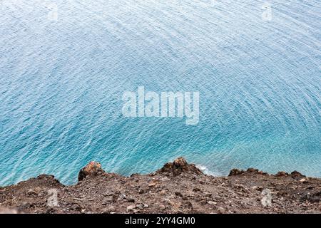 Una vista aerea mozzafiato di una costa tranquilla. Le limpide acque turchesi incontrano dolcemente un aspro litorale roccioso, creando un ambiente tranquillo e sereno Foto Stock