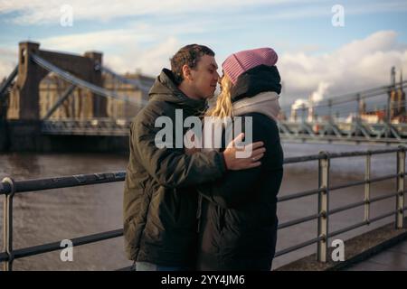 Una giovane coppia di coniugi, un uomo e una donna, condividono un abbraccio amorevole vicino a un fiume a Breslavia, in Polonia, durante la bella stagione. Si godono la compagnia reciproca Foto Stock