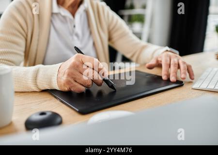 Un uomo anziano affascinante crea arte digitale utilizzando un tablet in un ambiente d'ufficio luminoso ed elegante. Foto Stock