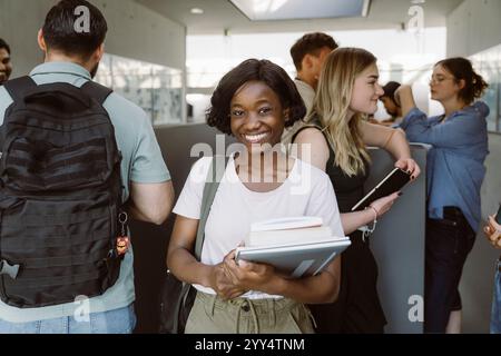 Ritratto di una studentessa felice che tiene dei libri mentre si trova al college Foto Stock