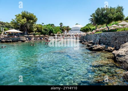 Rodi, Grecia 7 luglio 2024: Spiaggia all'interno delle sorgenti termali Kallithea (Terme Kalithea) a Rodi, Grecia. Il nuoto è un'attrazione popolare al mattino Foto Stock