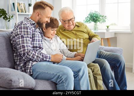 Figlio, padre e nonno che utilizzano Un notebook per l'intrattenimento a casa Foto Stock