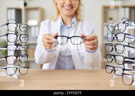 Giovane medico ottico felice che tiene gli occhiali in mano che lavora in clinica medica Foto Stock
