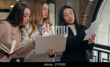 Donne d'affari affollate e impegnate tre donne multirazziali multietniche donne d'affari della diversità asiatiche giapponesi cinesi coreane ragazze caucasiche Foto Stock