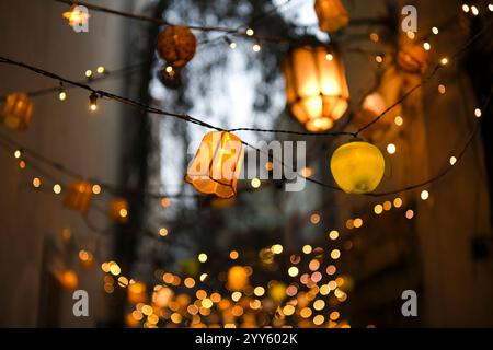 Luci colorate e lanterne su un albero di notte nel giardino. Decorazione serale per matrimoni, eventi o feste. Ghirlande di lampade su un albero Foto Stock