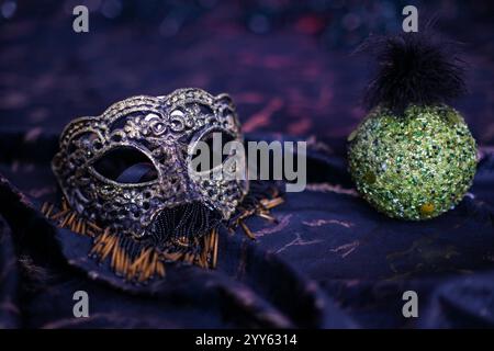 Elegante maschera veneziana e ornamenti decorativi verdi di natale evocano il mistero e la magia delle celebrazioni di carnevale. Foto Stock