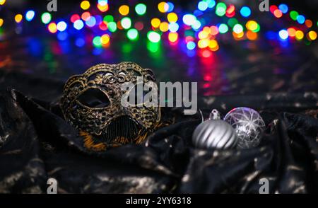 Elegante maschera veneziana e ornamenti decorativi verdi di natale evocano il mistero e la magia delle celebrazioni di carnevale. Foto Stock