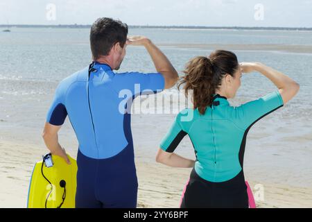 un paio di body boarder che guardano il mare Foto Stock