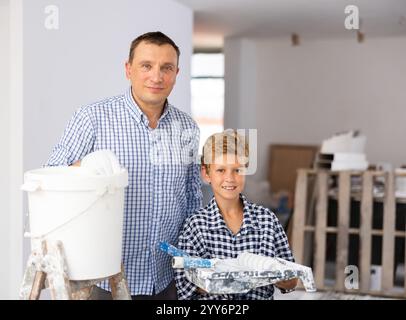 Ritratto di allegri padre e figlio con rulli di pittura in cantiere Foto Stock