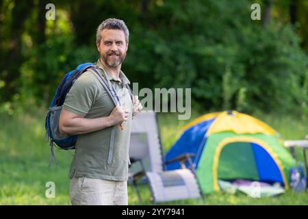 Uomo al campo nella foresta con la tenda. Uomo che fa trekking all'aperto in un giorno d'estate. Campeggio estivo e vacanza nella natura. Uomo in campeggio estivo. Avventura al campo. Escursioni Foto Stock