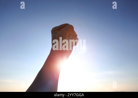 Luce solare che sorge sullo sfondo, luce solare brillante che splende tra le braccia fissate e allungate verso il cielo, simboleggiando i potenti desideri di Capodanno, Foto Stock