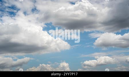 L'immagine cattura un cielo blu vibrante pieno di soffici nuvole bianche di varie dimensioni e forme. Le nuvole si spostano pacificamente, creando un sereno e. Foto Stock