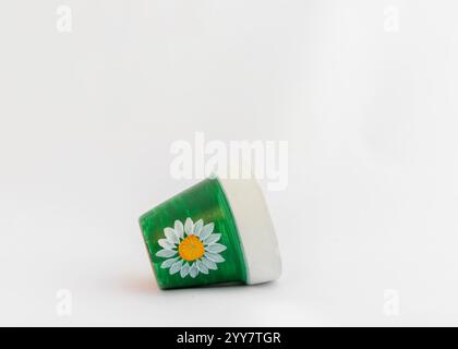 Fiori a margherita dipinti a mano su un piccolo vaso di argilla adagiato su uno sfondo bianco isolato Foto Stock