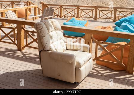 Scena illuminata dal sole con un'intima sedia reclinabile e vivaci sacchi di fagioli su un rustico ponte in legno. perfetto per il relax e le riunioni all'aperto Foto Stock