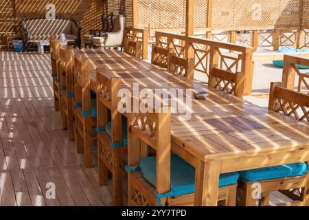 Elegante ambiente da pranzo all'aperto con mobili rustici in legno con design intricati completati da cuscini blu Foto Stock