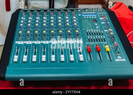 Vista ravvicinata di un colorato mixer di potenza di canale professionale posizionato sul tavolo in concerto, console di mixer audio. Foto Stock