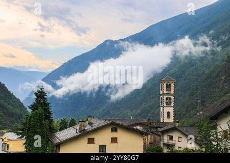 Torre della chiesa cattolica di San Carlo Borromeo nella città svizzera di Brusio al mattino con striscia nebbia che galleggia sullo sfondo della montagna. fa Foto Stock