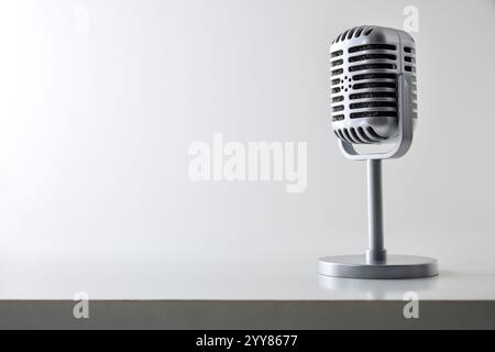 Sfondo con microfono a condensatore in metallo vintage con supporto su tavolo bianco e sfondo isolato dalla luce. Vista carattere. Foto Stock