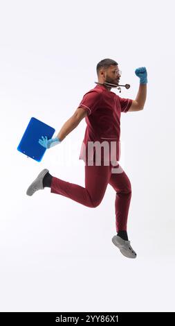 Giovane indiano, vestito da medico in uniforme, affrettati a portare il paziente sullo sfondo bianco dello studio. Ospedale. Foto Stock