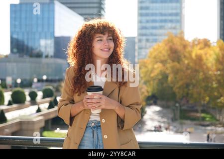 Donna d'affari felice che tiene in mano una tazza di caffè durante la pausa Foto Stock
