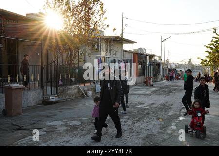 La gente cammina per la strada del campo di Domiz per i rifugiati curdi siriani a circa 18 km a sud-ovest della città di Duhok nella regione del Kurdistan. La provincia di Duhok ospita 92.000 rifugiati siriani su 275.000 rifugiati nella regione del Kurdistan in Iraq che sono migrati dallo scoppio della rivoluzione siriana nel 2011. La maggior parte di loro si rifiuta di tornare nel loro paese nonostante la caduta del regime di Bashar al-Assad per paura dello scoppio di conflitti armati tra le forze democratiche siriane (SDF) e l'esercito nazionale siriano sostenuto dai turchi o con Hayat Tahrir al-Sham e altre forze di opposizione che hanno preso parte Foto Stock