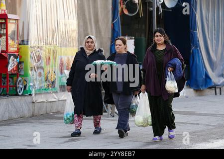 Le donne camminano per la strada del campo di Domiz per i rifugiati curdi siriani a circa 18 km a sud-ovest della città di Duhok nella regione del Kurdistan. La provincia di Duhok ospita 92.000 rifugiati siriani su 275.000 rifugiati nella regione del Kurdistan in Iraq che sono migrati dallo scoppio della rivoluzione siriana nel 2011. La maggior parte di loro si rifiuta di tornare nel loro paese nonostante la caduta del regime di Bashar al-Assad per paura dello scoppio di conflitti armati tra le forze democratiche siriane (SDF) e l'esercito nazionale siriano sostenuto dai turchi o con Hayat Tahrir al-Sham e altre forze di opposizione che hanno preso la truffa Foto Stock