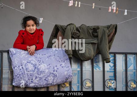 Un bambino si trova di fronte alla casa del campo di Domiz per i rifugiati curdi siriani a circa 18 km a sud-ovest della città di Duhok nella regione del Kurdistan. La provincia di Duhok ospita 92.000 rifugiati siriani su 275.000 rifugiati nella regione del Kurdistan in Iraq che sono migrati dallo scoppio della rivoluzione siriana nel 2011. La maggior parte di loro si rifiuta di tornare nel loro paese nonostante la caduta del regime di Bashar al-Assad per paura dello scoppio di conflitti armati tra le forze democratiche siriane (SDF) e l'esercito nazionale siriano sostenuto dai turchi o con Hayat Tahrir al-Sham e altre forze di opposizione che ha Foto Stock